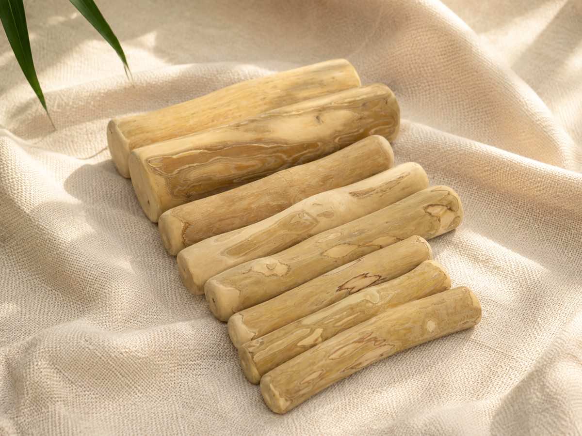 Coffee wood dog chews laid out in six sizes on natural linen
