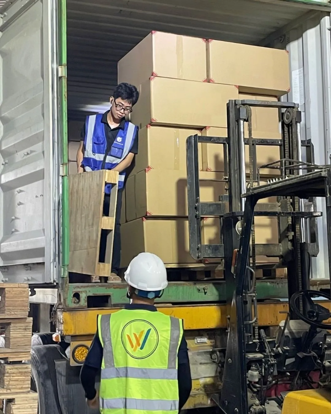 A forklift placing a palletised load of coffee wood dog chews into a container